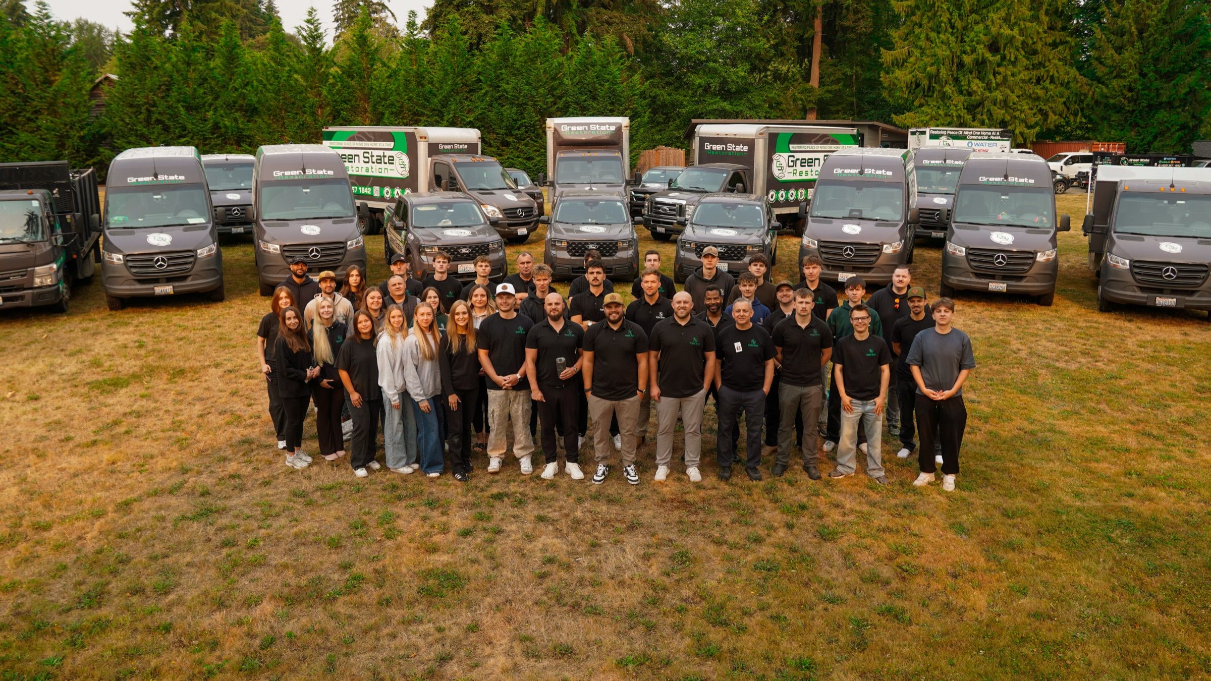 Green State Restoration full company team standing in front of branded restoration vehicles