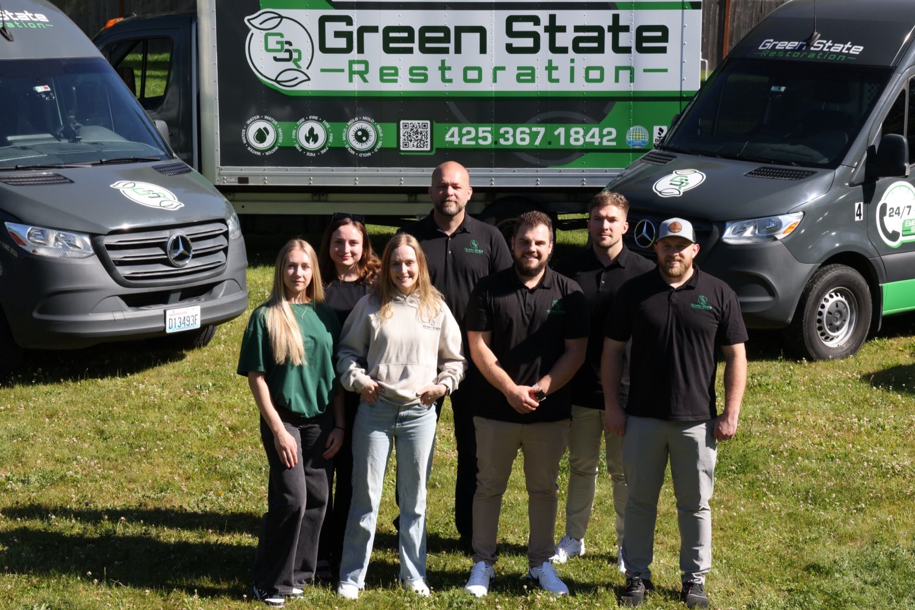 Green State Restoration leadership team standing in front of branded restoration vehicles