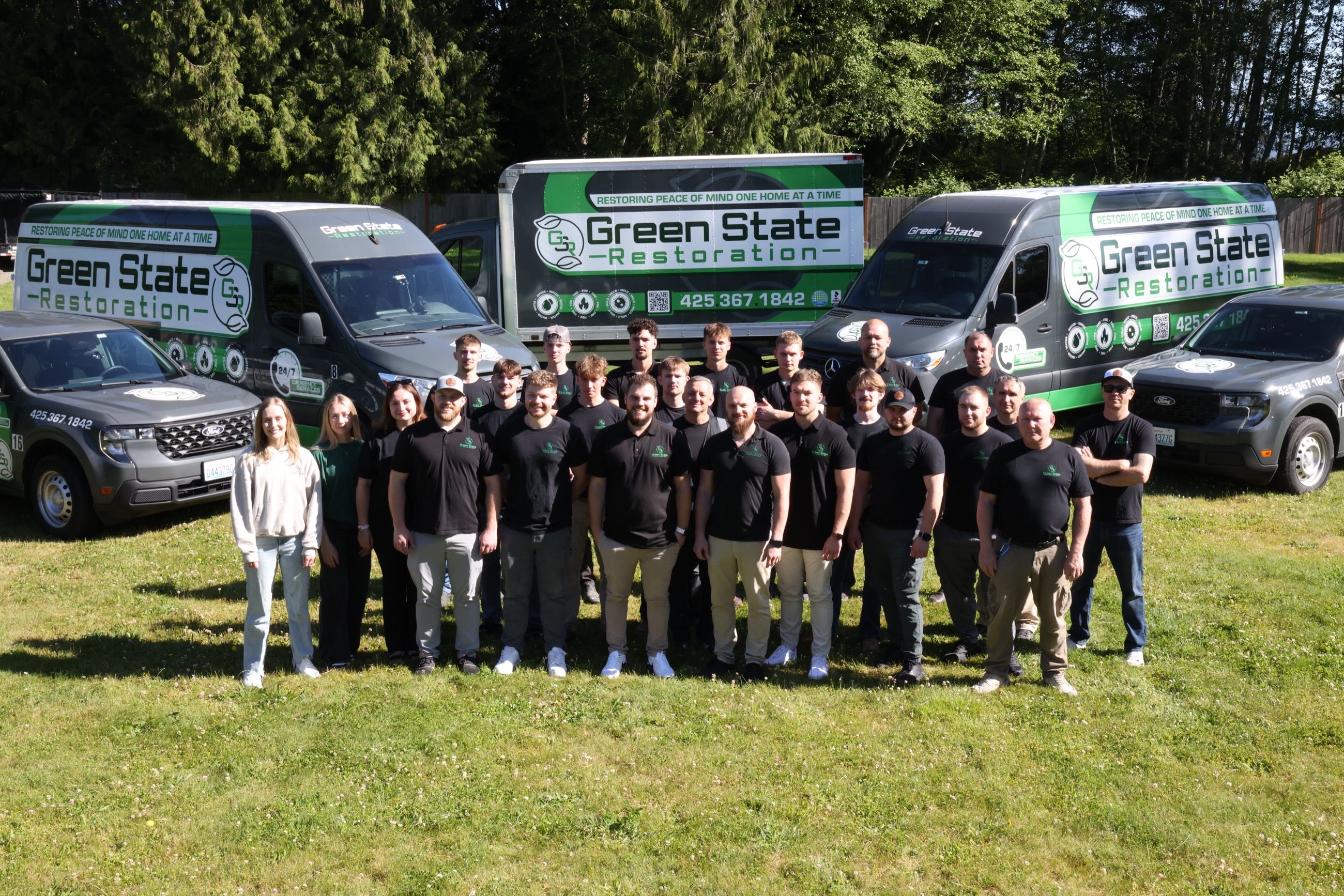 Green State Restoration team standing in front of branded restoration vehicles